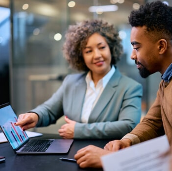 A woman showing a man reports on a laptop.