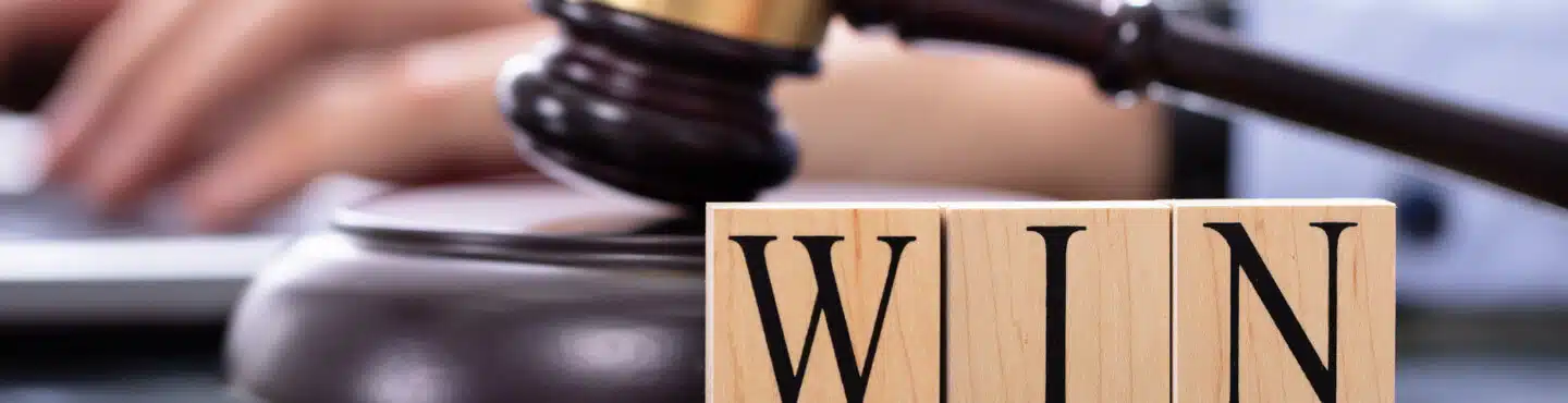 A gavel with three blocks in front of it spelling WIN.