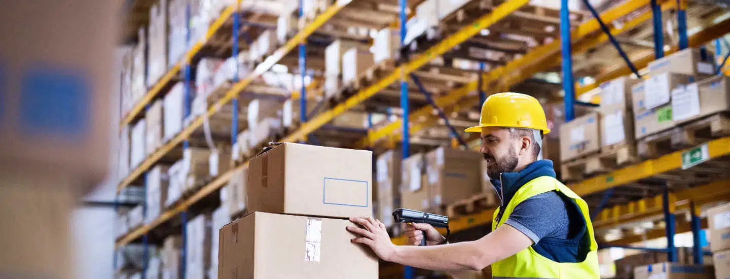 Man in a warehouse scanning a stack of boxes.