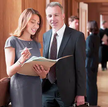 A female and male lawyer reviewing a folder of documents.