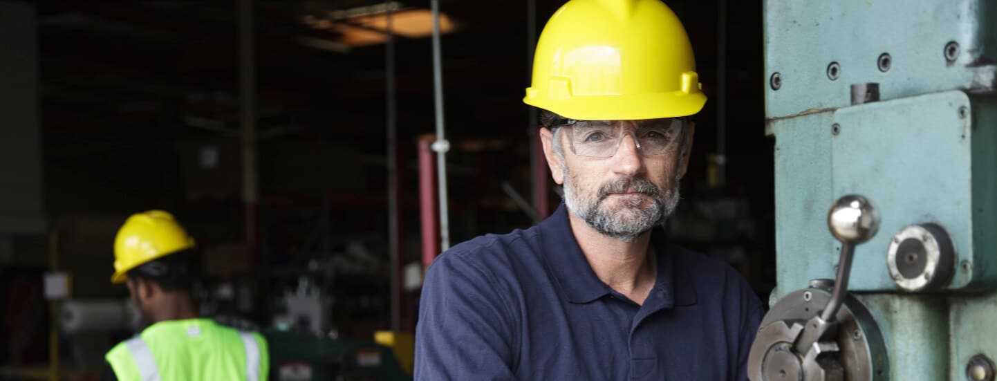 A close up of a man with a hard hat at a machine