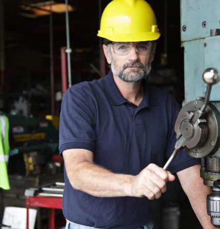 A close up of a man with a hard hat at an industrial machine