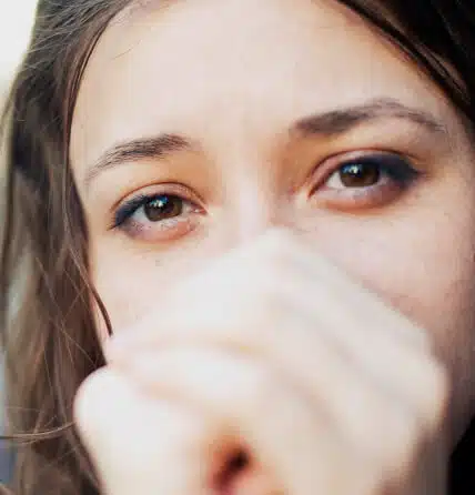 A close up of woman with her hands covering her face.